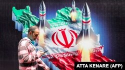 Мъж минава покрай пропаганден постер в Техеран, изобразяващ изстрелване на ракети от територията на Иран на фона на иранското знаме, 15 април 2024 г.