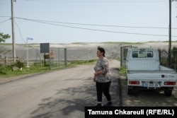Maya Svanidze walks in front of the entrance to the grounds for the potential deep sea port at Anaklia. Construction began on the project before an initial contract was canceled in 2020, leaving behind piles of sand and earth.