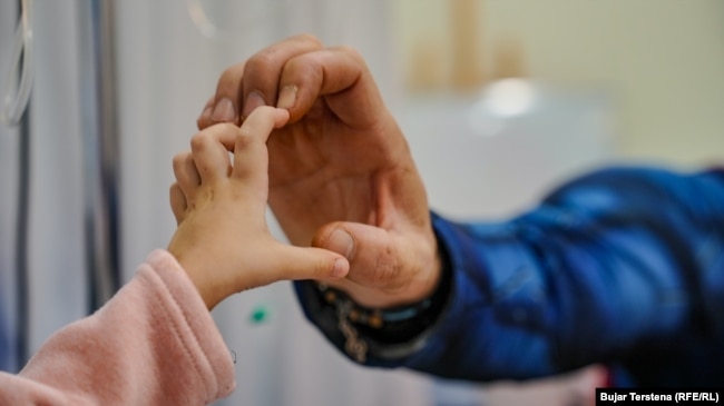 Një fëmijë në repartin e Onkologjisë pediatrike në QKUK zgjat njërën dorë drejt një vullnetari për ta bërë formën e një zemre.