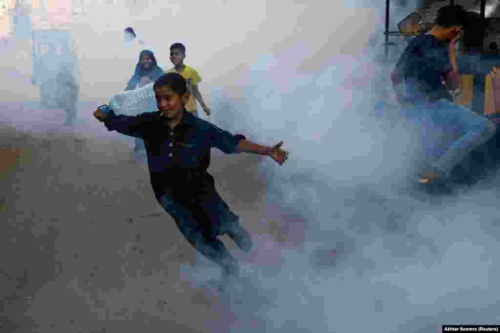 A boy runs amid a fumigation vapor cloud being sprayed to stem the spread of the dengue virus in Karachi, Pakistan.