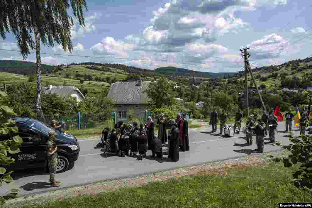 Priftërinjtë duke bekuar një familje në rrugë gjatë ceremonisë së varrimit të një ushtari ukrainas që u vra në vijën e frontit pranë Kupjansk, në Opak, Ukrainë.