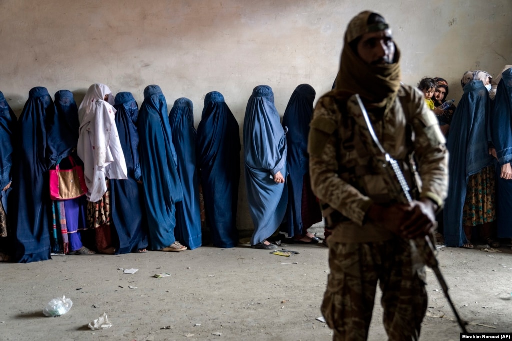 Një luftëtar taliban qëndron roje ndërsa gratë presin në radhë të marrin racione me ushqim që i shpërndante një grup humanitar, në Kabul, Afganistan, 23 maj 2023.
