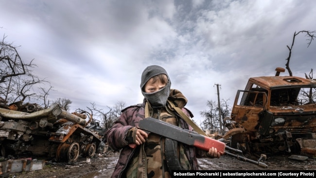 9-летний мальчик позирует с деревянным автоматом, подаренным ему украинскими солдатами после успешного контрнаступления. Село Шестовица, Черниговская область. Апрель 2022 года