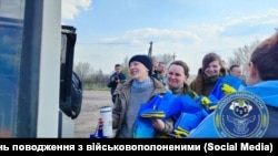 Повернення українських бранців 10 квітня 2023 року. У них в руках чашки від Червоного Хреста 