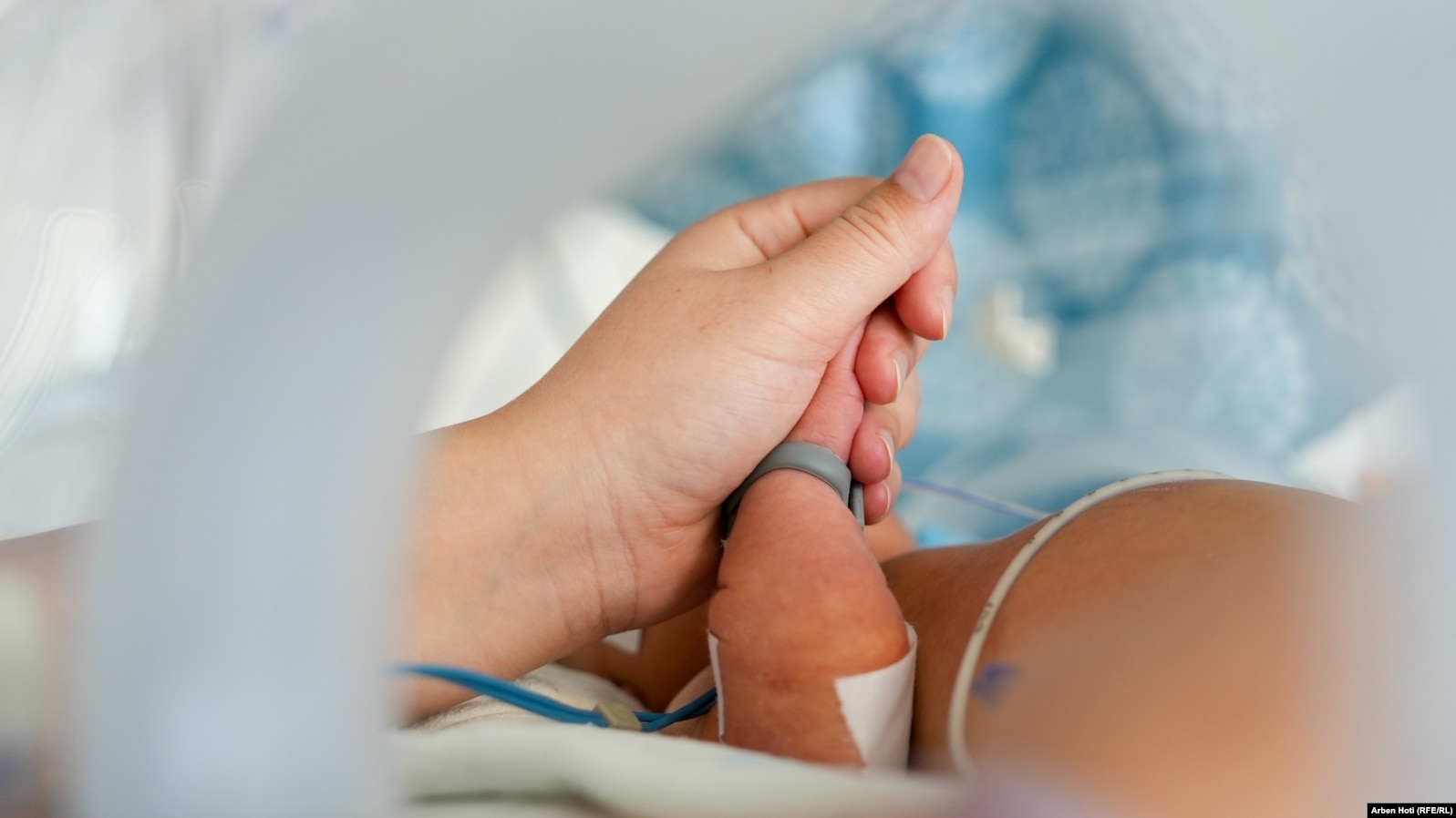 Një nënë i mban dorën foshnjës së saj në inkubator.