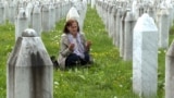 A woman prays amid the gravestones of Srebrenica victims at a memorial cemetery in Potocari. 