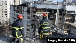 Munkások eltávolítják a törmeléket egy lakóépületből, miközben felújítanak egy részben megsemmisült lakótömböt Harkiv külvárosában 2023. január 25-én