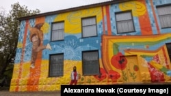 Alexandra Novak în fața unei clădiri proaspăt pictate. Imagine din arhiva personală