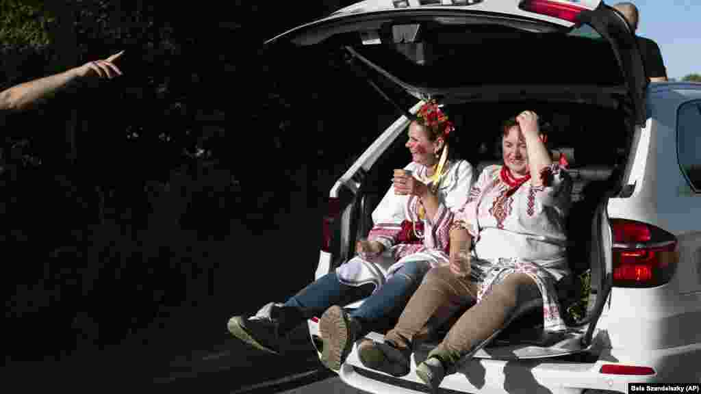 Мамы молодожёнов едут в багажнике автомобиля в день свадьбы. Родители жениха и невесты были одеты в традиционные украинские костюмы&nbsp;