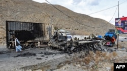 A man walks past charred truck containers torched by the Baloch Liberation Army (BLA) in the central Bolan district in Balochistan Province on January 30.