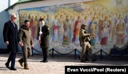 Президенти України і США ідуть повз стіну Михайлівського собору у Києві. 20 лютого 2023 року