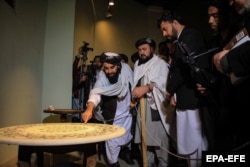 Purtătorul de cuvânt al talibanilor, Zabiullah Mujahid (stânga), vizitează Muzeul Patrimoniului pentru a marca Ziua Culturii la Kabul, la 13 martie 2022.