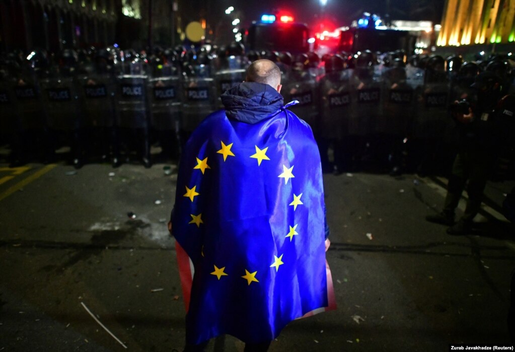 Një demonstrues i mbështjellë me një flamur të Bashkimit Evropian gjatë protestave në Tbilisi, Gjeorgji, kundër projektligjit për "agjentët e huaj", për të cilin kritikët thonë se përfaqëson një ndryshim autoritar dhe mund të dëmtojë përpjekjen e Gjeorgjisë për t'u bashkuar me BE-në, më 9 mars. Më 10 mars, ligjvënësit gjeorgjianë votuan pro anulimit të projektligjit.