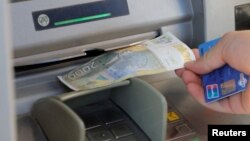 Muškarac podiže srpski dinar sa bankomata u Mitrovici, Kosovo, 1. februara 2024.