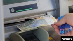 Një person duke tërhequr dinarë nga një bankomat në Mitrovicë të Veriut. 1 shkurt 2024. 