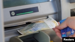 Një burrë duke tërhequr një bankënotë prej 2.000 dinarësh serbë nga një bankomat në Mitrovicën e Veriut, Kosovë, më 1 shkurt 2024.