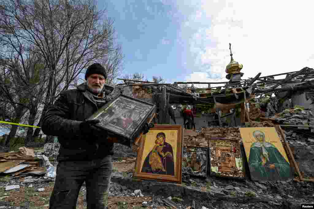 Чоловік тримає ікону на тлі знищеної російською атакою у ніч проти 16 квітня церквою у Комишувасі Запорізької області