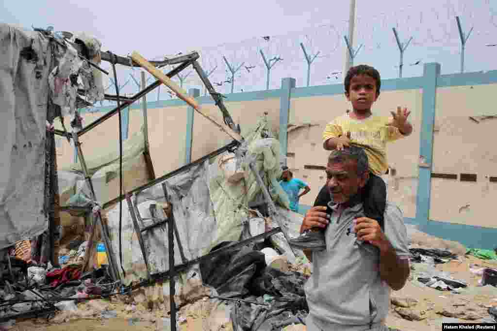 یک پدر و فرزند بر ویرانه&zwnj;های برجا مانده از حمله روز دوشنبه اسرائیل به محل اسکان آوارگان 