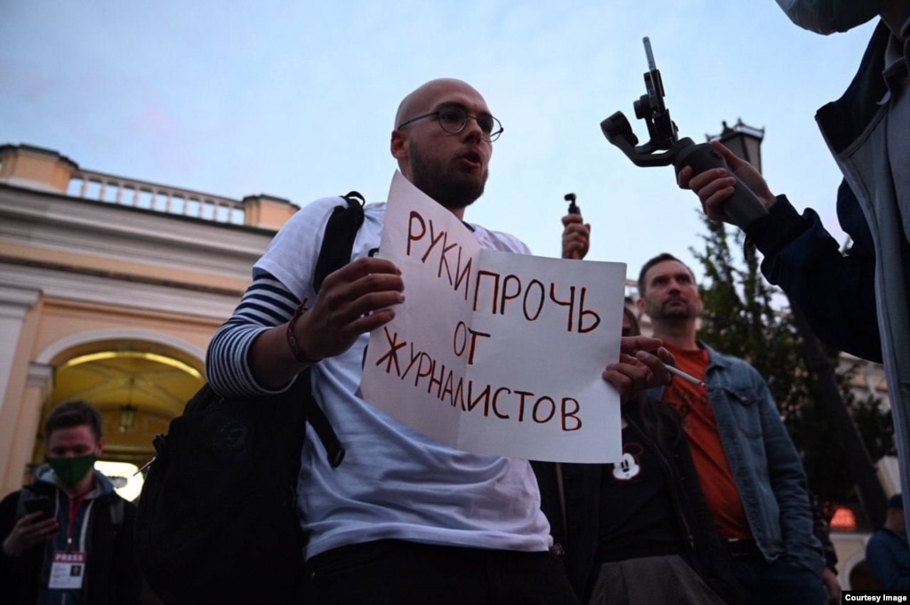 Arseny Vesnin mban një pankartë ku shkruan "Hands of Journalists" në një protestë në Shën Petersburg, para se të largohej nga Rusia.