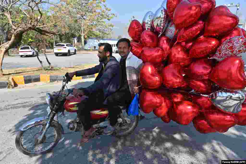 Men ride a bike after buying heart-shaped balloons at a flower market on Valentine&#39;s Day in Islamabad on February 14.