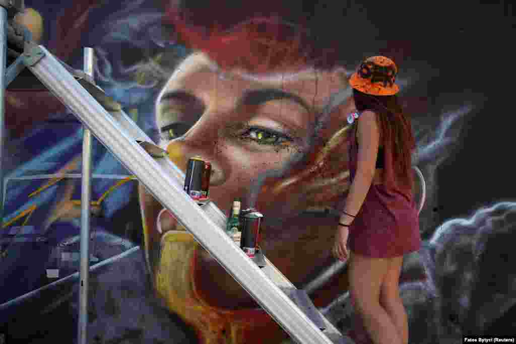 Liliana Demitri, a graffiti artist from Italy, paints a mural as part of the Meeting of Styles graffiti festival in Kosovo&#39;s capital, Pristina, on July 29. The city is trying to revitalize its drab image with vivid graffiti murals that will help transform public spaces into more inviting, vibrant areas.