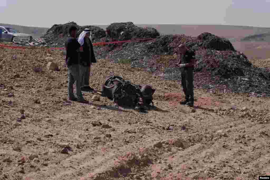 Një oficer policor dhe dy banorë duke inspektuar më 14 prill, pranë Aradit, në Izrael, mbeturinat e një shtytëseje rakete që, sipas autoriteteve izraelite, plagosi rëndë një vajzë 7-vjeçare pasi Irani nisi dronë dhe raketa në drejtim të Izraelit.