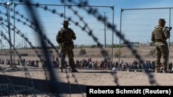 Пограничники охраняют границу с Мексикой, за которой мигранты ждут возможности попасть в центр обработки CBP (таможенно-пограничной службы США в Эль-Пасо. Техас, США. 10 мая 2023 года