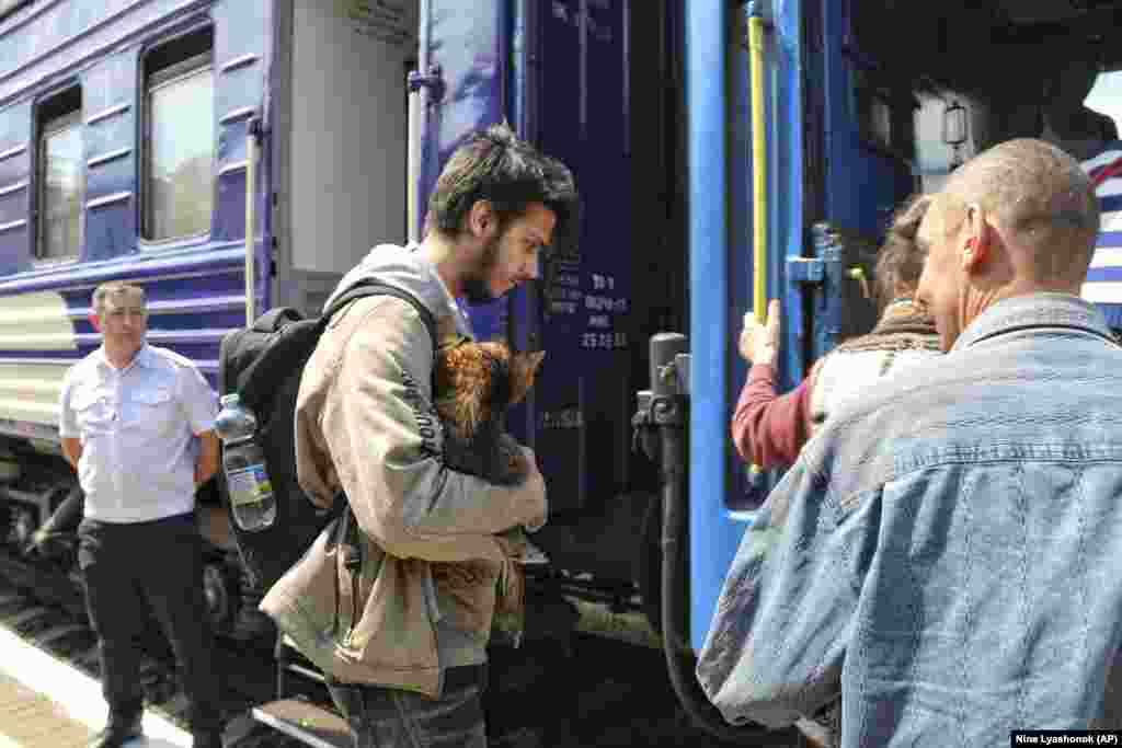 Луѓе се качуваат на воз за евакуација на железничката станица во Херсон.
