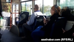 Aşqabadda avtobusda əyləşən bir qadın telefonuna baxır