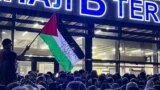 A local man waves a Palestinian flag with a message reading "Daghestan Stands By You" during a pro-Palestinian rally at Makhachkala airport after the arrival of a scheduled flight from Tel Aviv on October 29.