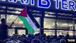 A local man waves a Palestinian flag with a message reading "Daghestan Stands By You" during a pro-Palestinian rally at Makhachkala airport after the arrival of a scheduled flight from Tel Aviv on October 29.