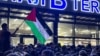 Un bărbat flutură un steag palestinian pe care scrie „Daghestan este alături de tine” în timpul unui miting pro-palestinian la aeroportul din Mahacikala, după sosirea unui zbor de linie de la Tel Aviv, pe 29 octombrie.