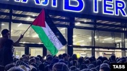 Мужчина с палестинским флагом с надписью «Дагестан с вами!» во время антисемитского выступления в аэропорту Махачкалы после прибытия рейса из Тель-Авива