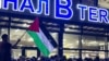 Një burrë e valëvit një flamur palestinez me mesazhin "Dagestani është me ju" gjatë një tubimi pro-palestinez në aeroportin e Makaçkalës, pas mbërritjes së një aeroplani nga Tel Avivi më 29 tetor, 2023.