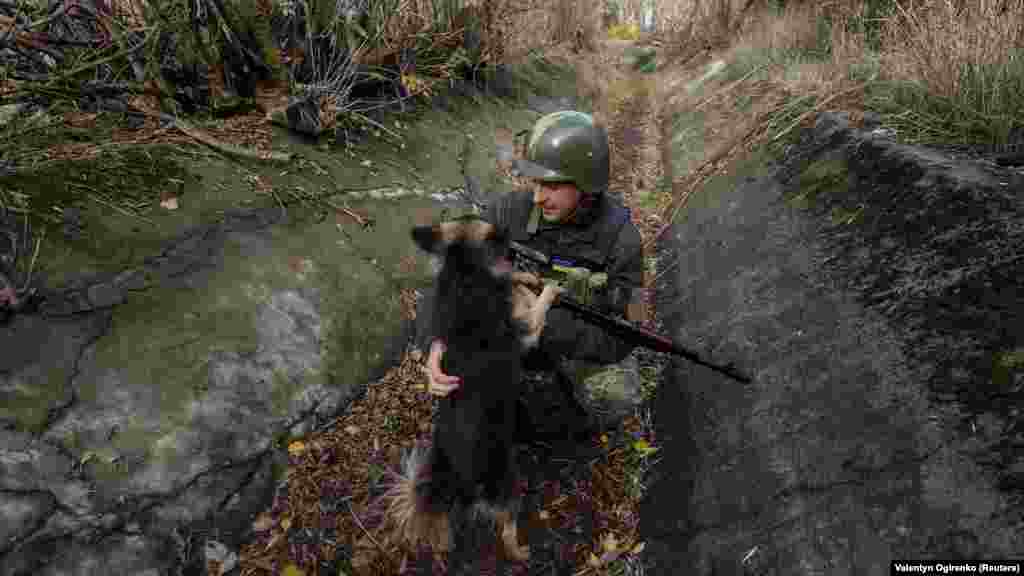 Iván simogatja a kutyáját a frontvonal egyik állásában, a Mikolajivi területen