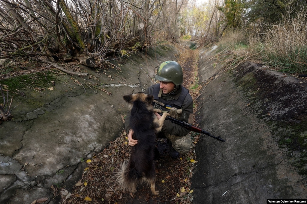 Ivani, ushtar ukrainas, përkëdhel një qen në një pozicion në vijën e frontit në rajonin e Mikolajivit, 26 tetor 2022.