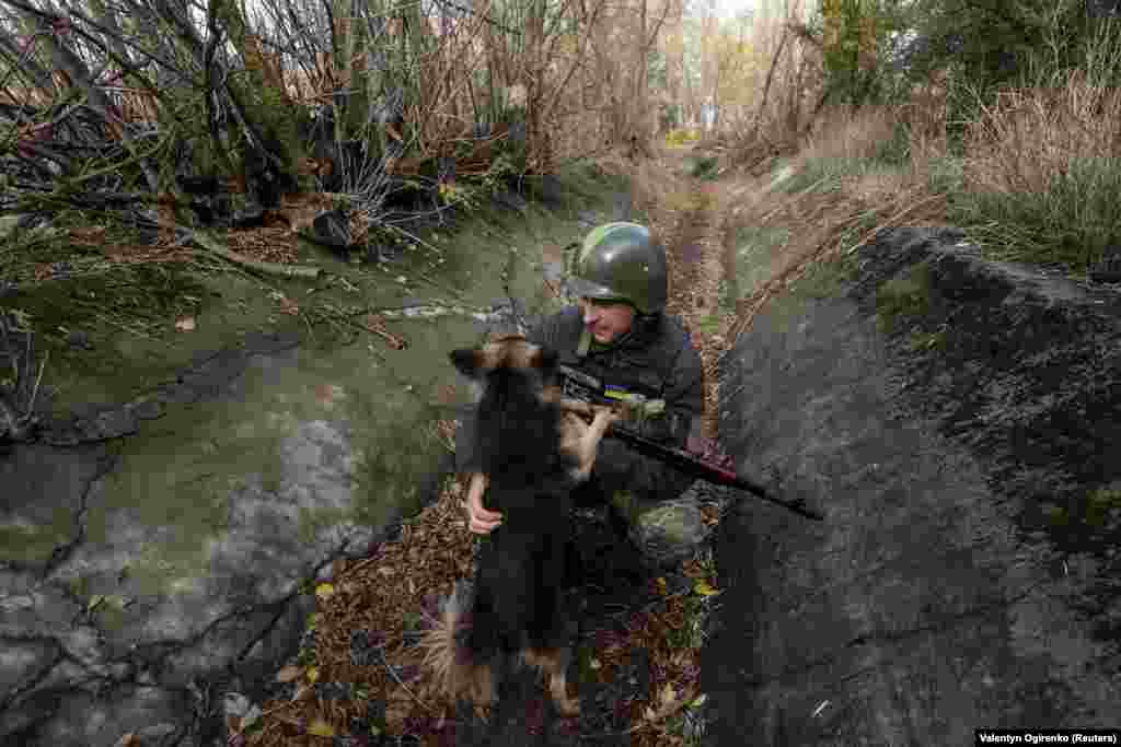 Ukrainian soldier Ivan pets a dog at a position on the front line in the Mykolayiv region on October 26, 2022.