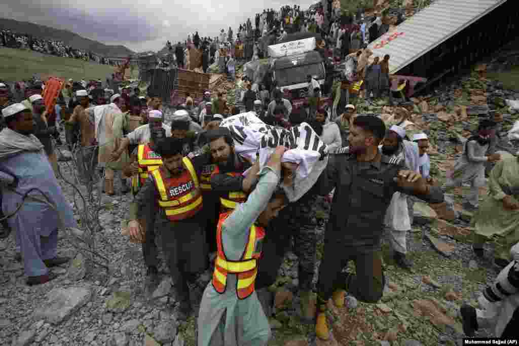 Rescue workers and volunteers carry a body they recovered from the rubble at the site of a landslide near the border town of Torkham in Pakistan.