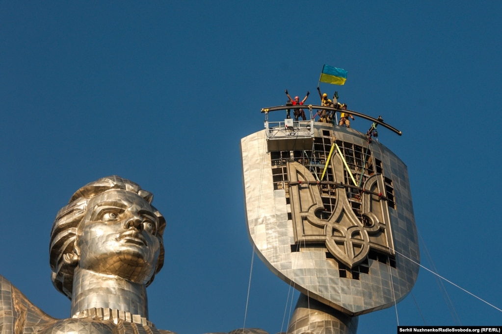 Punëtorët festojnë pas instalimit të Tridentit ukrainas në Monumentin e Atdheut të Kievit më 6 gusht 2023. Tridenti masiv zëvendësoi një emblemë sovjetike.