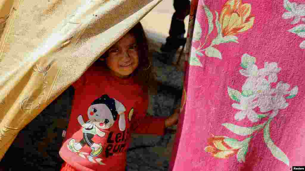 Egy gyermek néz ki egy sátorból, amely jelenleg az otthona a Gázai övezet déli részén fekvő Rafahban 2023. december 11-én. A palesztinokat régóta kísérti az általuk nakbanapnak, azaz katasztrófanapnak nevezett esemény, amikor 1948-ban, Izrael állam létrejöttekor hétszázezer palesztint fosztottak meg otthonától. Sokukat elűzték, vagy a szomszédos arab államokba menekültek, többek között Jordániába, Szíriába és Libanonba, ahol sokan közülük vagy a leszármazottaik még mindig menekülttáborokban élnek. Néhányan Gázába mentek