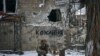 Soldat ucrainean în Bahmut, regiunea Donețk, Ucraina, 14 februarie 2023. Pe zid scrie „Dragoste, iar pe indicatorul stradal scrie „Strada Independenței”.