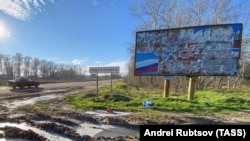 A road sign at the edge of town reads Nova Kakhovka, December 2022. The flag of Russia, whose forces have occupied Nova Kakhovka since the start of Russia's full-scale invasion of Ukraine, is visible on another sign.