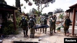 Израильские солдаты эвакуируют тела погибших в кибуце Кфар Аза