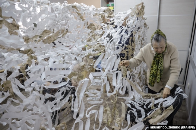 Російська пенсіонерка плете маскувальну сітку для фронту