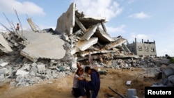 Dy vajza palestineze pranë një shtëpie të rrënuar nga lufta mes Izraelit dhe Hamasit në Rafah, Gazë, 21 prill 2024.
