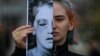 Снимката е илюстративна. На нея се вижда активистка на движението за правата на жените "Делик", която държи снимка на половин лице на жертва на домашно насилие, по време на протест в Букурещ, 4 март 2020 г.