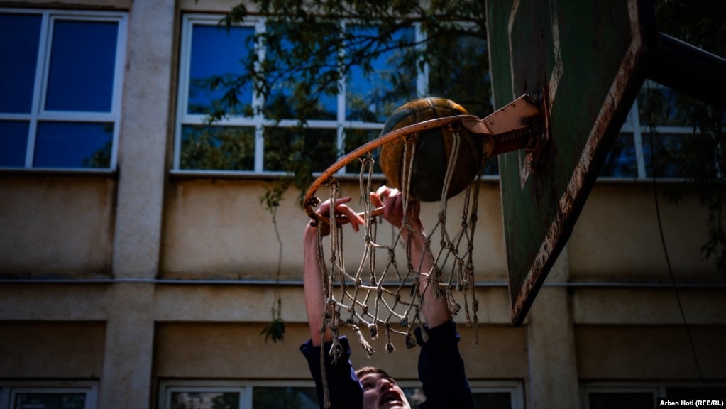 Një nxënës duke lozuar në oborrin e shkollës, ku gjendet një kosh basketbolli.&nbsp;
