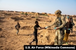 Офицер ВВС США Лоренцо Беннетт, член дислоцированной в Нигере "409-й экспедиционной эскадрильи сил безопасности", раздает питьевую воду детям. Окрестности "Авиабазы 201", Нигер, 6 января 2023 года