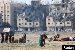Palestinienii își cară puținele lucruri rămase în urma loviturilor israeliene asupra clădirilor rezidențiale din orașul Hamad, finanțat de Qatar, în sudul Fâșiei Gaza, 2 decembrie 2023.