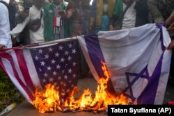 Мусульманські протестувальники спалюють прапори США та Ізраїлю під час мітингу проти ізраїльських авіаударів у Газі біля посольства США в Джакарті, Індонезія, 11 жовтня 2023 року